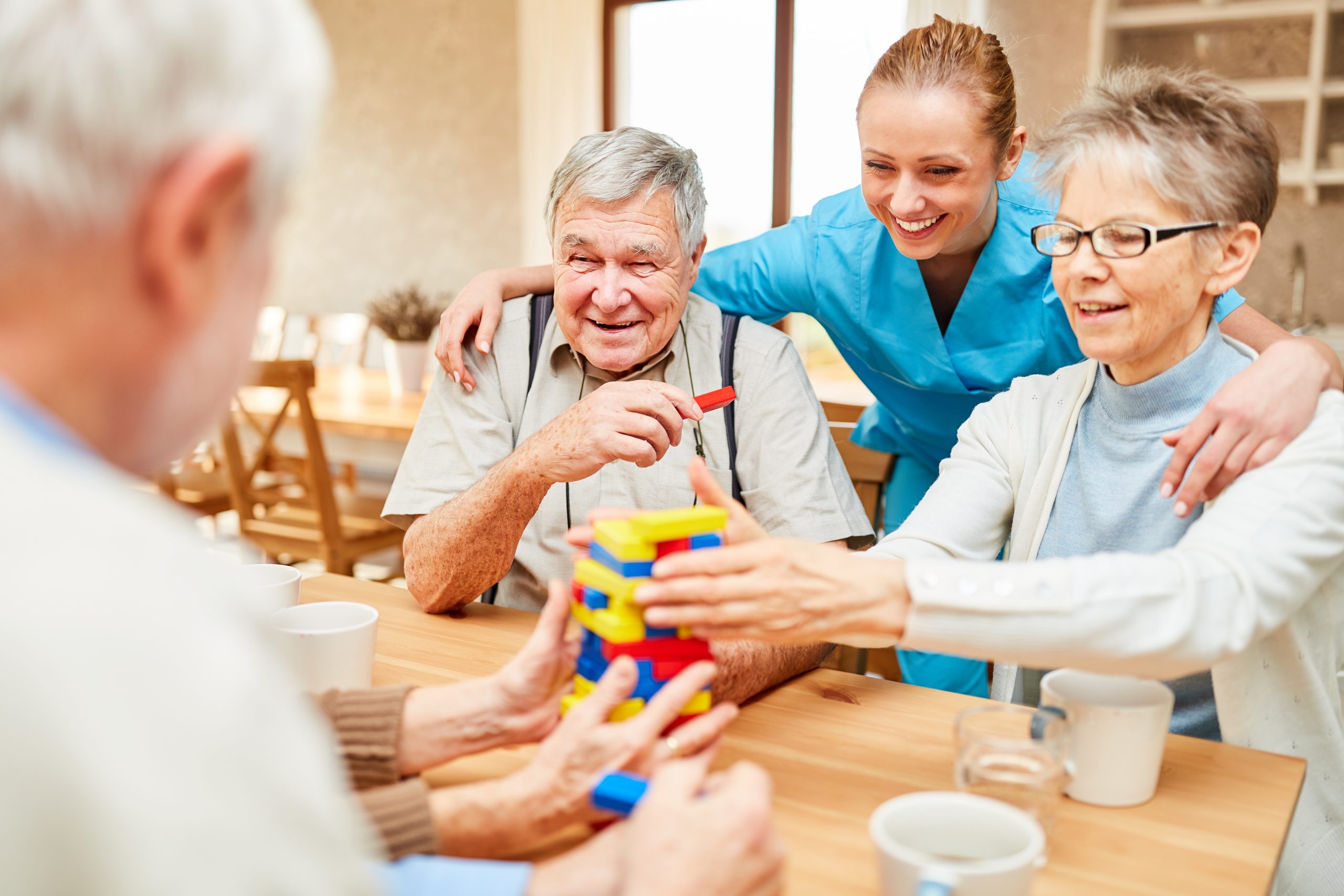 Altenpflegerin kümmert sich im demente Senioren beim Spielen mit Bausteinen