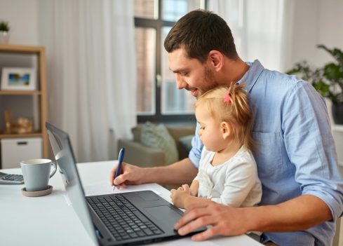 multi-tasking, freelance and fatherhood concept - working father with baby daughter and laptop computer at home office