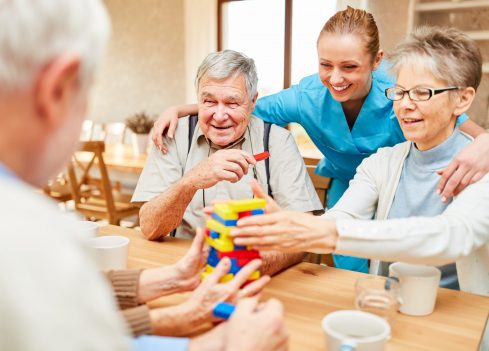 Altenpflegerin kümmert sich im demente Senioren beim Spielen mit Bausteinen
